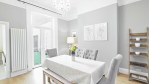 A dining room with a table set for four, a chandelier, and a view of the outdoors. - Host Stay Victorian Seahouse (Saltburn-by-the-Sea)