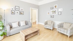 A living room with a grey sofa, a plaid armchair, a wooden coffee table, and a floor lamp. - Host Stay Victorian Seahouse (Saltburn-by-the-Sea)