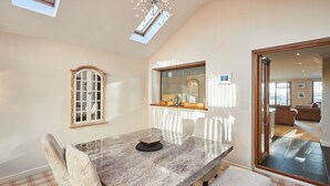 A dining area with a marble table, cushioned chairs, a bench, and a large mirror reflecting the room. - Host Stay The Chimneys (Alnwick)