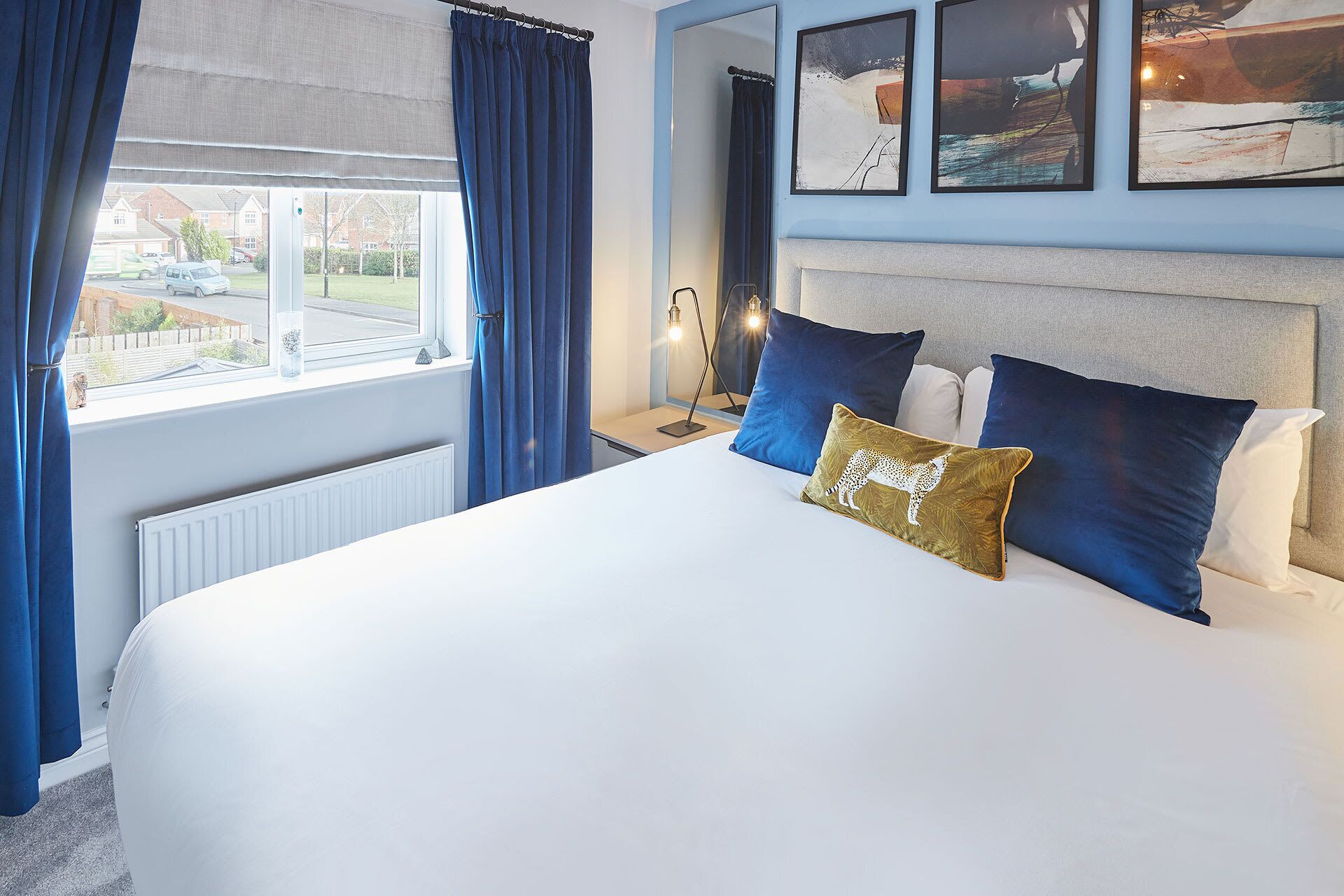 Quarto de hotel com uma cama grande, vista para o exterior e obras de arte na parede.