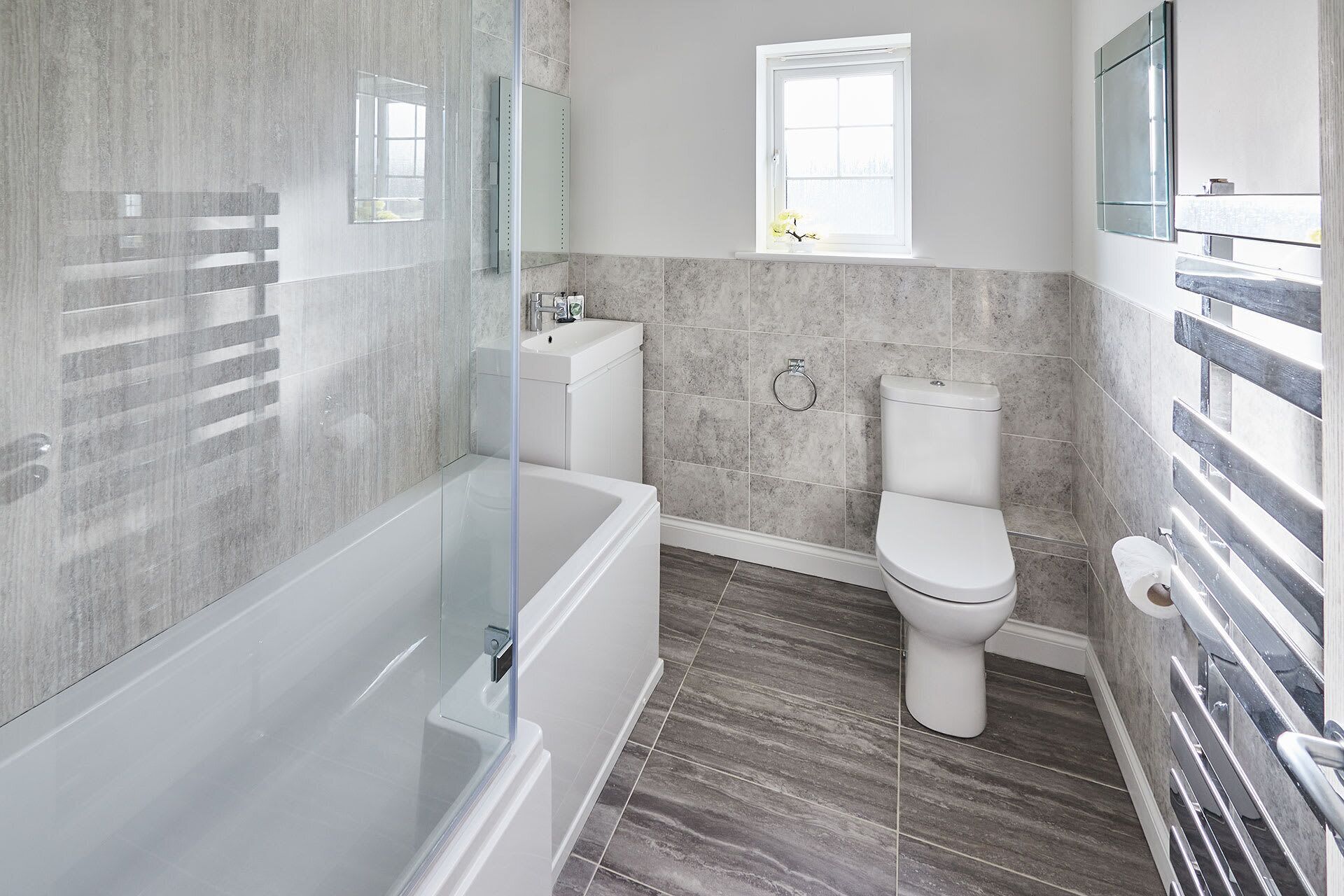 A modern bathroom with a glass-enclosed shower, a toilet, and a sink.