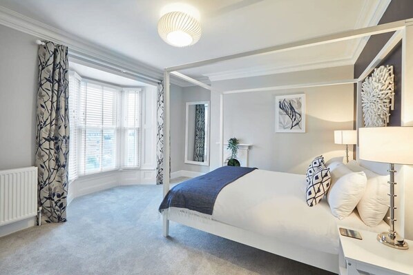 Cozy retreat with a large bed, window, and nightstand.