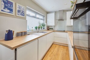 Enjoy cooking in this well-lit kitchen with a sink, oven, and range hood.