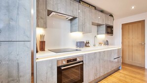 Una cocina moderna con armarios grises, horno empotrado, microondas y tostadora.