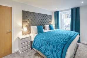 Relax in a serene bedroom with a tufted headboard, a comfortable bed, and a nightstand with a lamp.