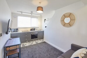 Modern kitchen with oven, sink, and window above the countertop. Features a dining table and comfortable seating area.