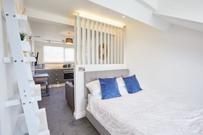 Cozy retreat with a large bed, storage ladder, and desk area.