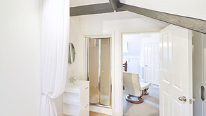A bedroom with a bed, a white bathroom with a shower, and a door leading to another room. - Host Stay Park Place Apartment (Whitby)