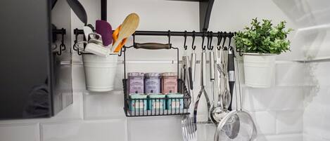 A kitchen with utensils hanging on a rack, a plant, and spice containers.