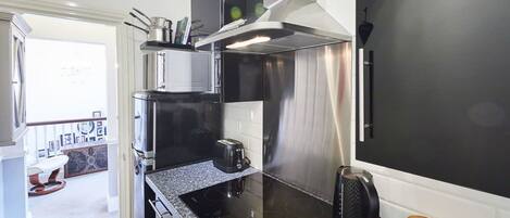 Una cocina moderna con campana extractora de acero inoxidable, horno empotrado y cafetera.
