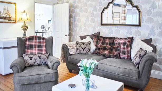 A living room with a grey sofa set, matching armchairs, and a white coffee table. - Host Stay Park Place Apartment (Whitby)