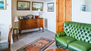 Une pièce avec un canapé en cuir vert, un meuble en bois et un tapis.