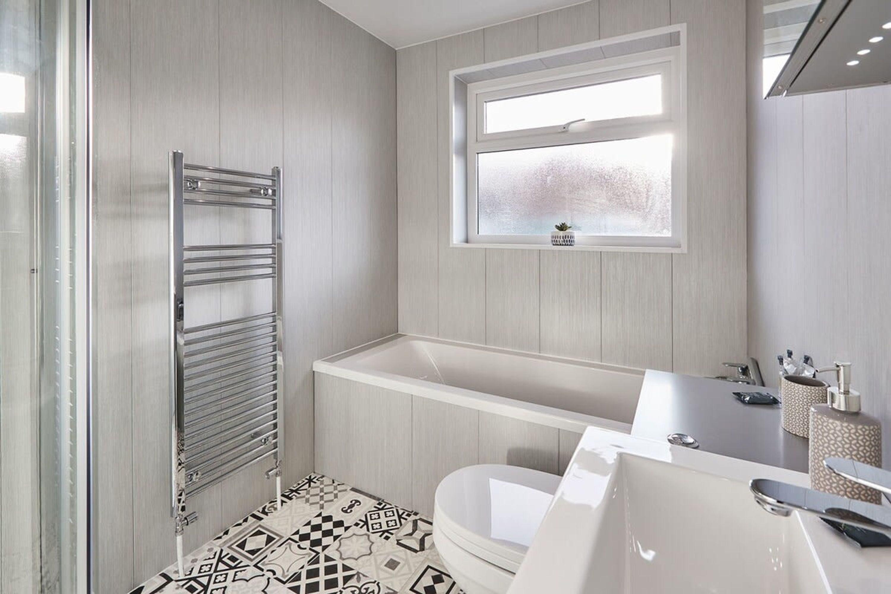 A modern bathroom with a freestanding bathtub, a towel rack, and a window above the sink.