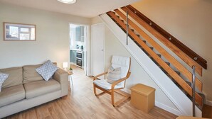 Un salon avec un canapé, un fauteuil, une petite table et un escalier.