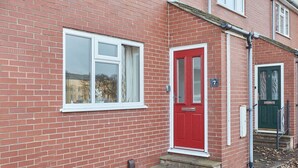 Une maison en briques rouges avec une fenêtre à cadre blanc et une porte rouge.