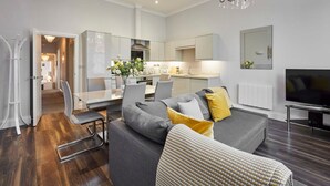 A modern living room with a grey sofa, a dining area, and a kitchen. - Host Stay Brooklands Timeless (Scarborough)