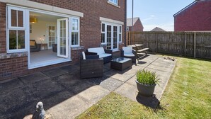 A brick house with a patio area featuring outdoor furniture and a potted plant. - Host Stay Driftwood (Chathill)