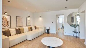 A modern living room with a white sofa, a round coffee table, and a large mirror. - Host Stay Taylor Street (Seahouses)