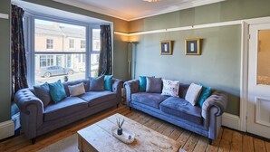 A living room with two sofas, a coffee table, and a large window with curtains. - Host Stay High Street (Saltburn-by-the-Sea)