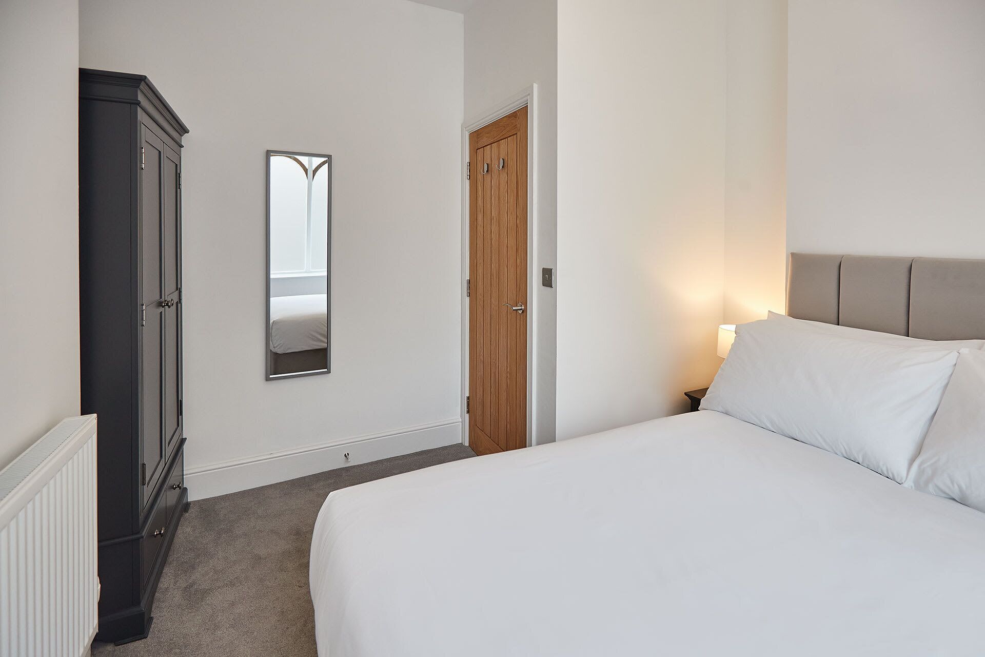 Ein Schlafzimmer mit Bett, Kleiderschrank, Spiegel und Tür.