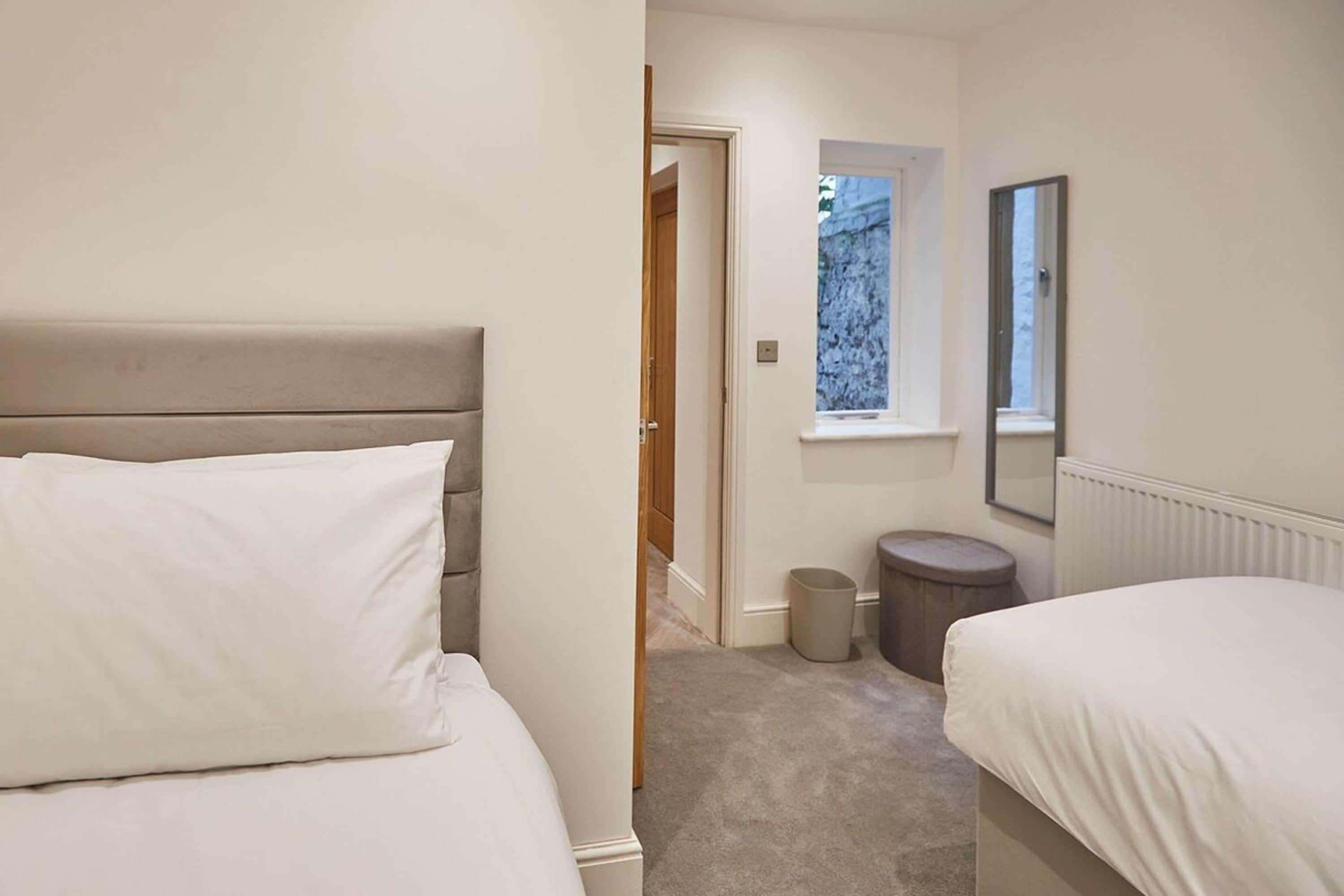 A bedroom with two beds, a window, and a radiator.