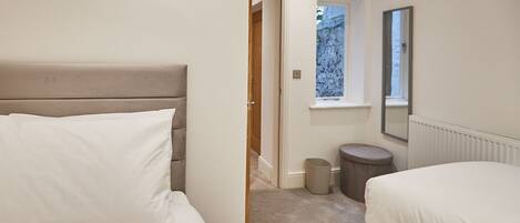 A bedroom with two beds, a window, and a radiator.