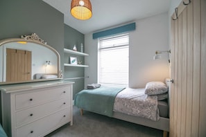 Cozy retreat with a comfortable bed, dresser, and mirror.