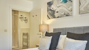 Ein Schlafzimmer mit Bett, Nachttisch, Lampe, einer Tür und einer Wand mit abstrakter Kunst.