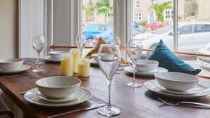A dining table set with white bowls, plates, and wine glasses, candles, and a blue pillow. - Host Stay Beckside (Pickering)