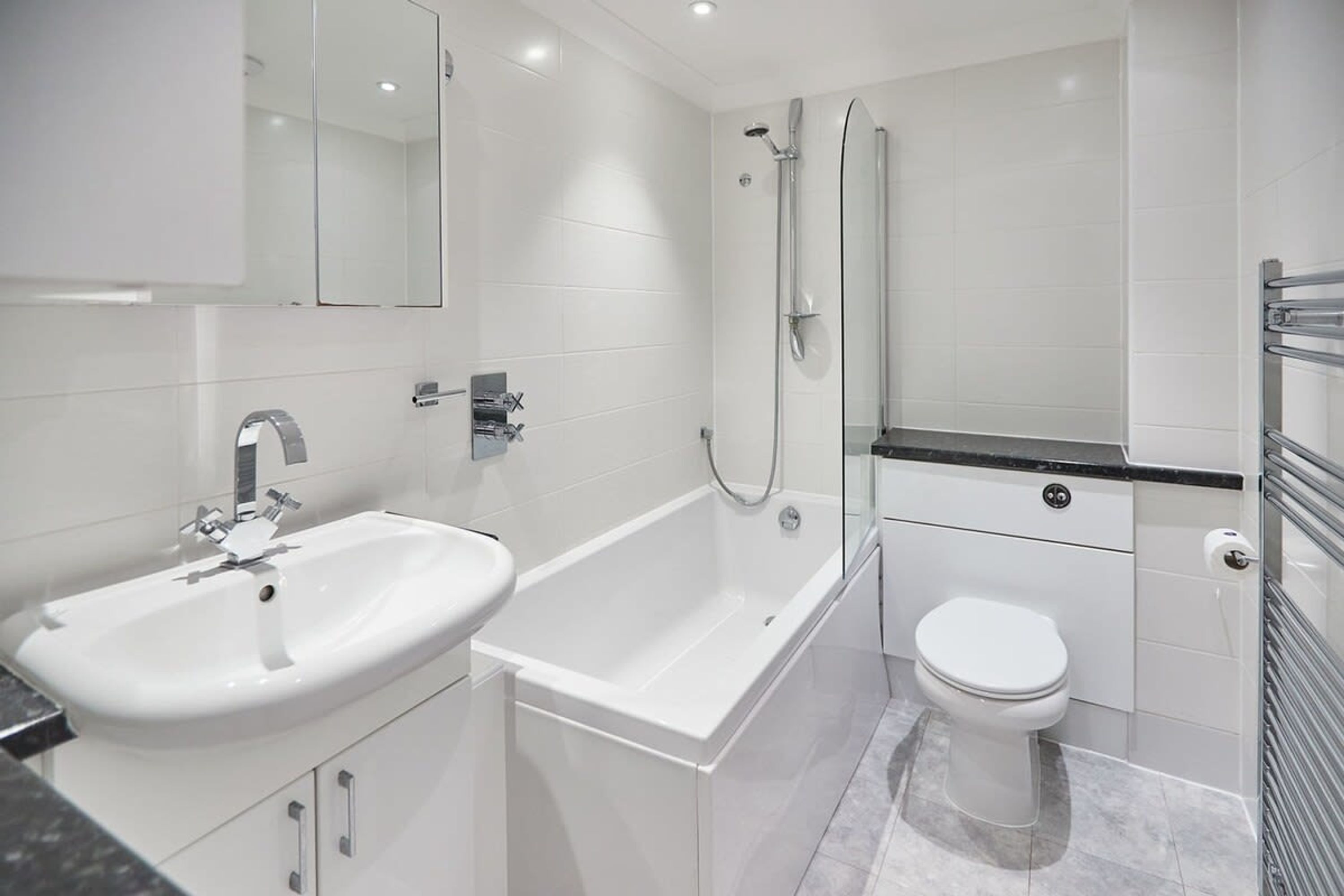 A modern bathroom with a white sink, bathtub, and toilet.