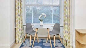 A dining area with a table and two chairs, a vase with flowers, and a patterned rug. - Host Stay Thamesview (Staines)