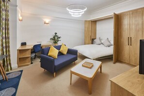 Quarto de hotel moderno com cama, sofá, escrivaninha e televisão.
