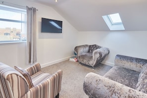 Relax in a serene space with a seating area, flat-screen TV, and natural light pouring in through a skylight.