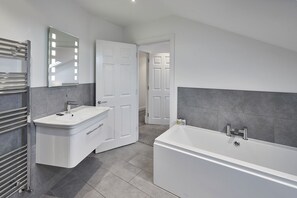 Enjoy a serene bathroom experience with a spacious bathtub and separate shower area.