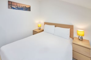 Relax in a serene space with a large bed, bedside tables, and a beautiful coastal painting.