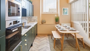 A modern kitchen with a built-in oven, a sink, and a dining area with a table set for four. - Host Stay No 33 (North Shields)