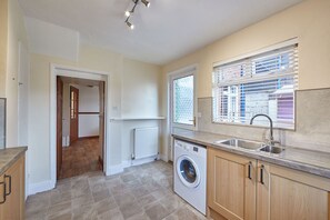 Kitchen area with washer and dryer, sink, and window with blinds.