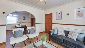 Una sala moderna con un sofá, sillones, una mesa de centro y un comedor con una mesa y sillas.
