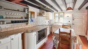 A kitchen with white cabinets, a built-in oven, and a dining area with a table and chairs. - Host Stay Hall Garth (Pickering)