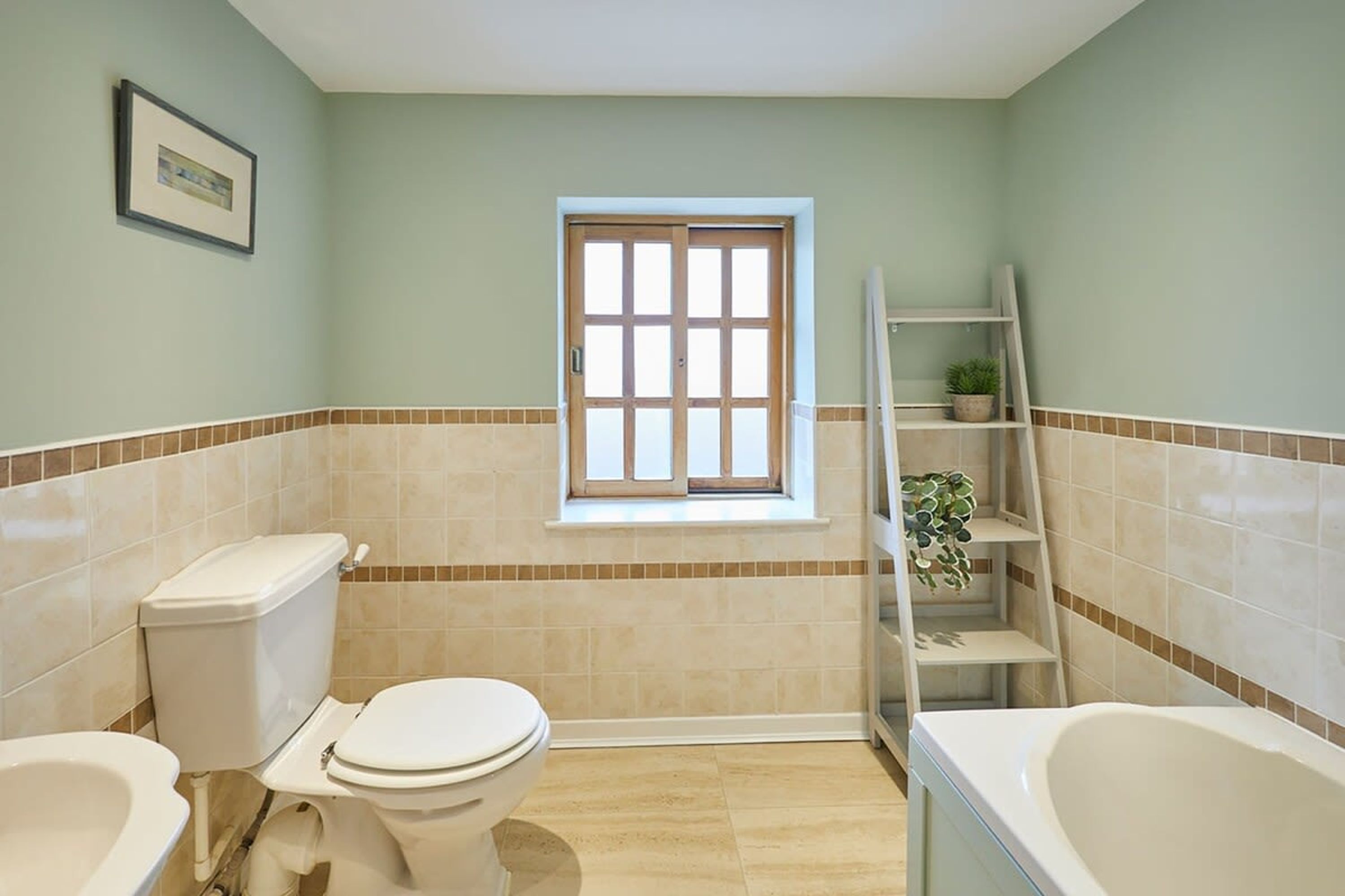 Une salle de bain comprenant des toilettes, un bidet et une baignoire. Il y a une fenêtre donnant sur l’extérieur.