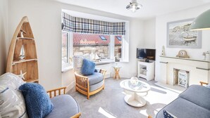A living room with a large window, a fireplace, and a television. - Host Stay Mumbles Cottage (Whitby)