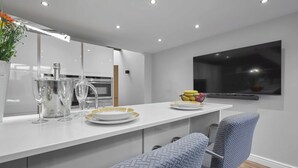 Une cuisine moderne avec des meubles blancs, un four encastré et une grande fenêtre.