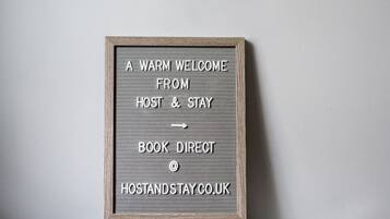 A framed sign with text welcoming guests to Host & Stay, directing them to book directly at hostandstay.co.uk.