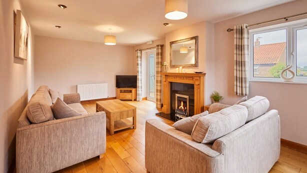 A living room with a fireplace, two sofas, a coffee table, and a television. - Host Stay Dove Cottage (Pickering)