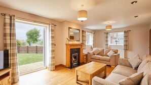 A living room with a fireplace, sofa, and television. - Host Stay Dove Cottage (Pickering)