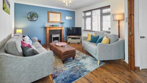 A living room with a fireplace, two grey sofas, a coffee table, and a TV. - Host Stay Cleveland Rest (Saltburn-by-the-Sea)