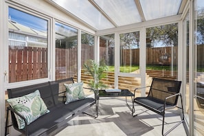 A conservatory with a glass ceiling, a sofa, a chair, and a small table.
