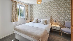 A bedroom with a large bed, a nightstand, a chair, and a window with curtains. - Host Stay Cleveland Rest (Saltburn-by-the-Sea)