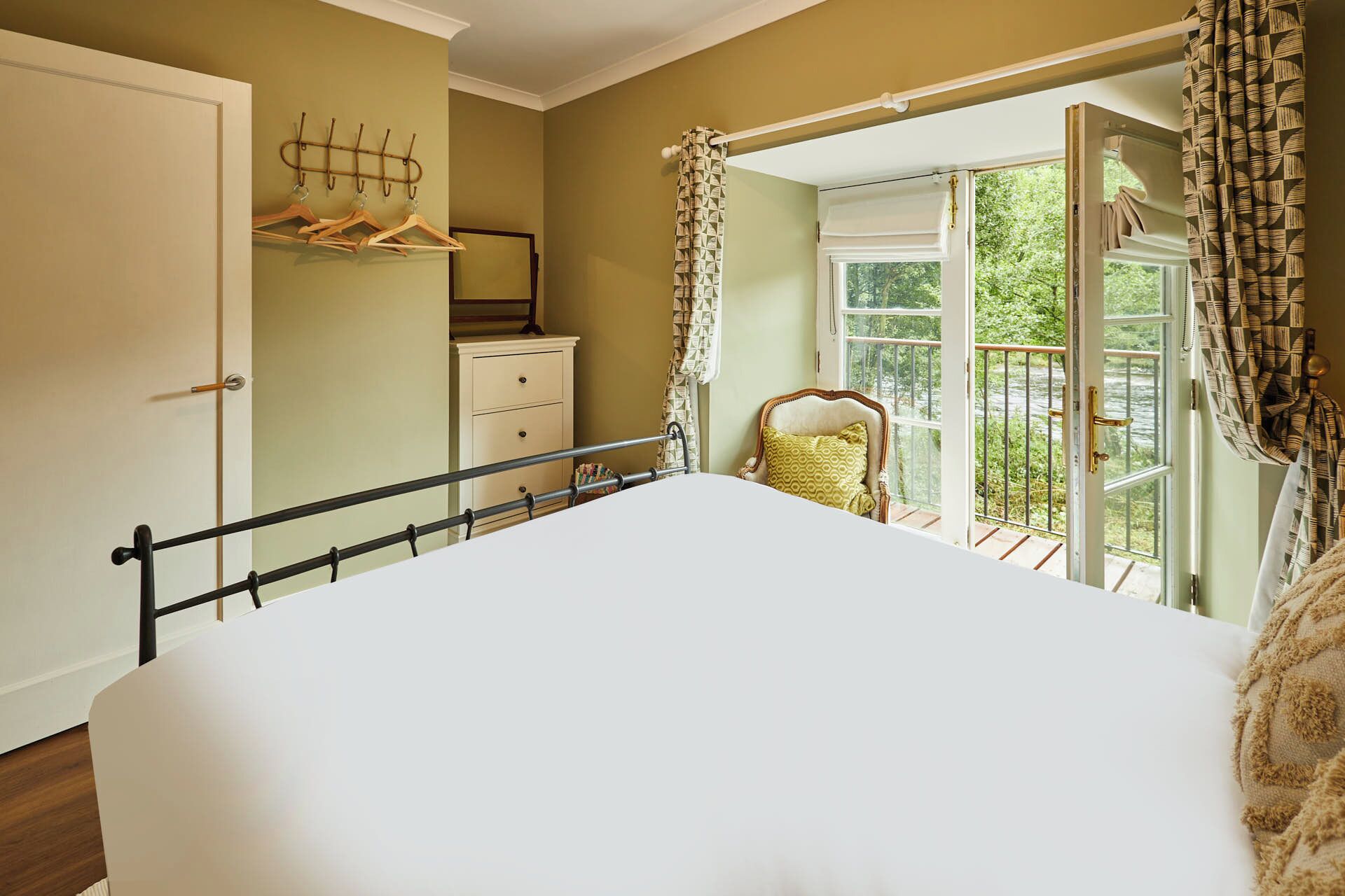 A bedroom with a bed, a dresser, a chair, and a window with curtains.