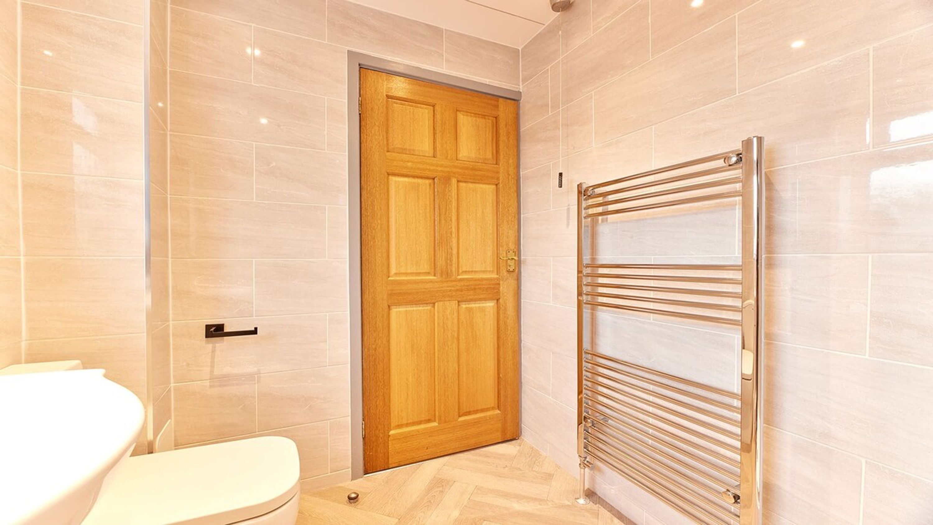 Een badkamer met een houten deur, een wit toilet en een handdoekhouder.